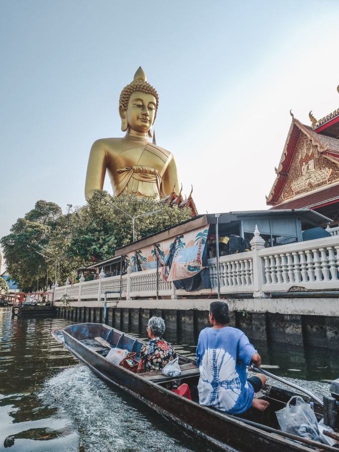 Pirogue devant un Bouddha géant près d’un temple thaïlandais
