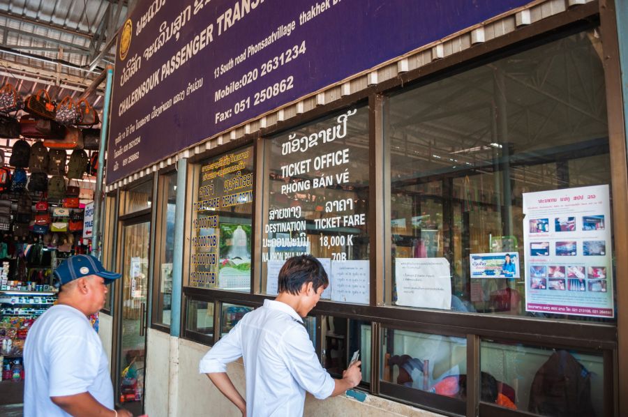 Hommes devant guichet de billets de transport à Vientiane