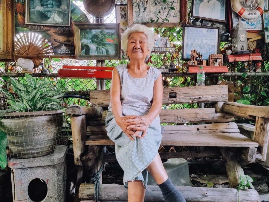 Femme âgée assise sur un banc entourée de souvenirs