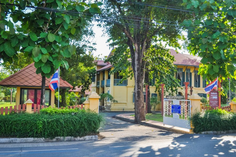 Bâtiment jaune thaïlandais entouré d'arbres et de drapeaux
