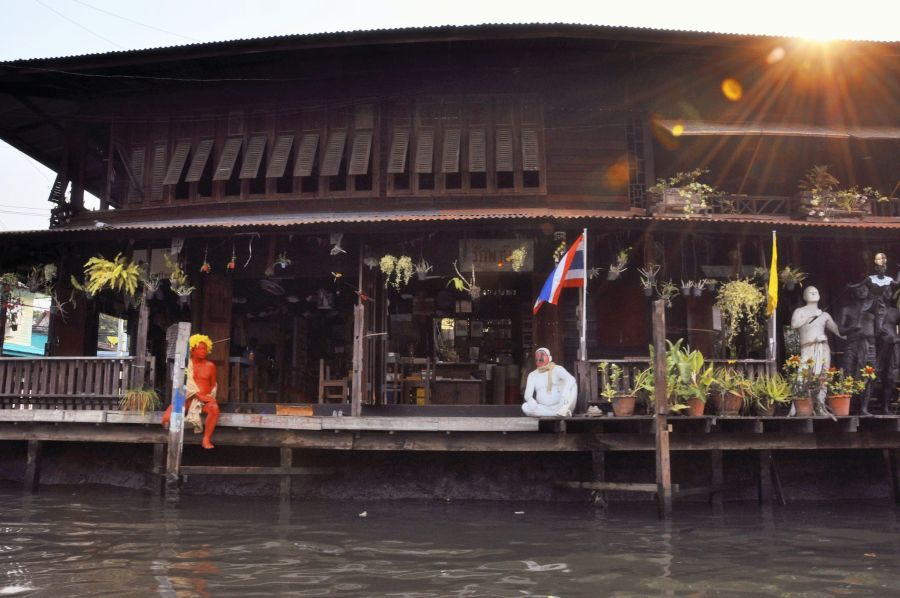 Maison en bois sur pilotis, statues et drapeaux thaïlandais