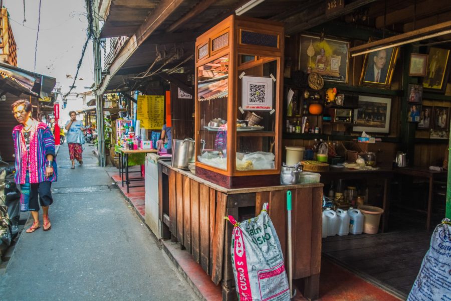 Rue étroite avec étal de cuisine thaïlandaise et passants
