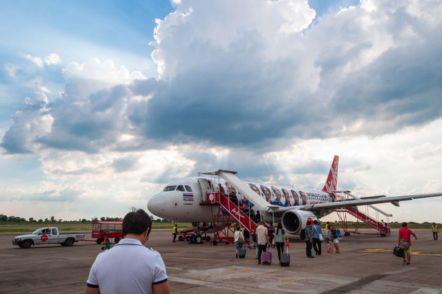Passagers embarquant dans un avion AirAsia sous un ciel nuageux