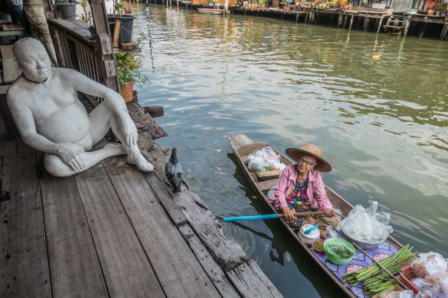 Vendeuse en barque près d’une statue au bord du canal