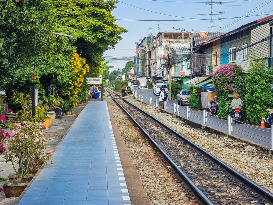 Voie ferrée traversant un quartier fleuri à Bangkok