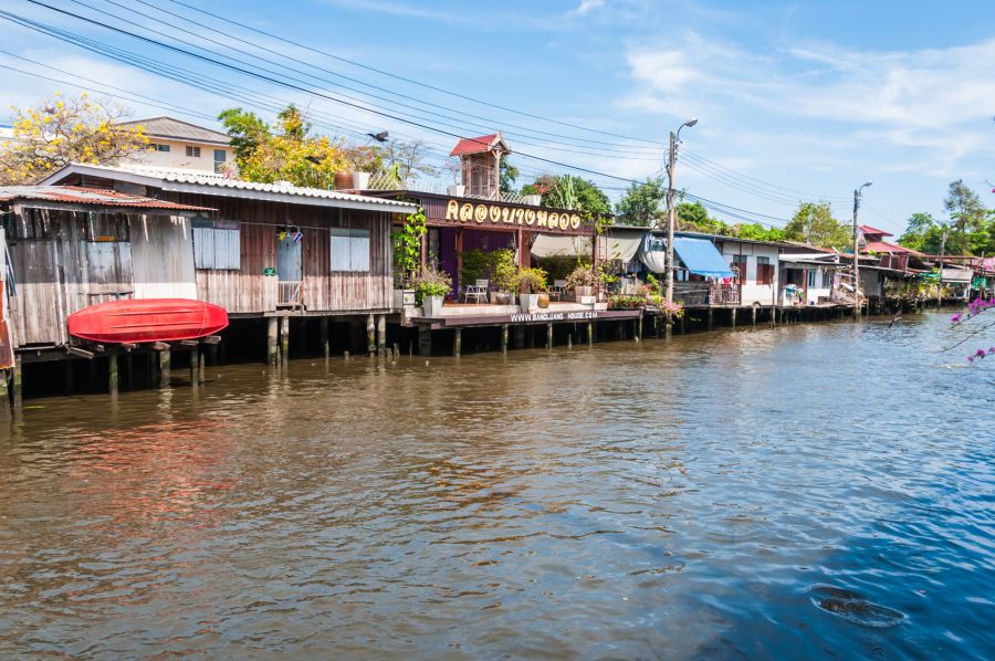 Maisons sur pilotis et canoë rouge au bord d’un canal