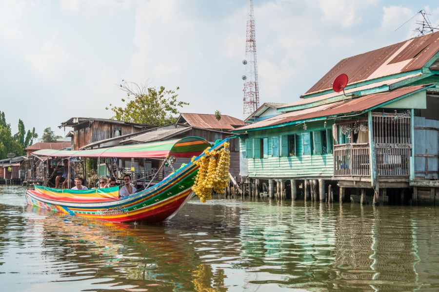 Bateau coloré naviguant devant des maisons sur pilotis