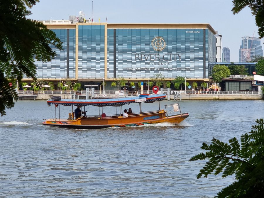 Bateau traditionnel devant River City Bangkok sur le fleuve
