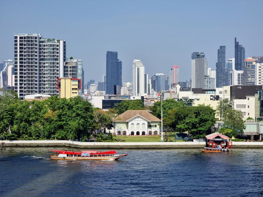 Bateau sur le fleuve devant les gratte-ciel de Bangkok