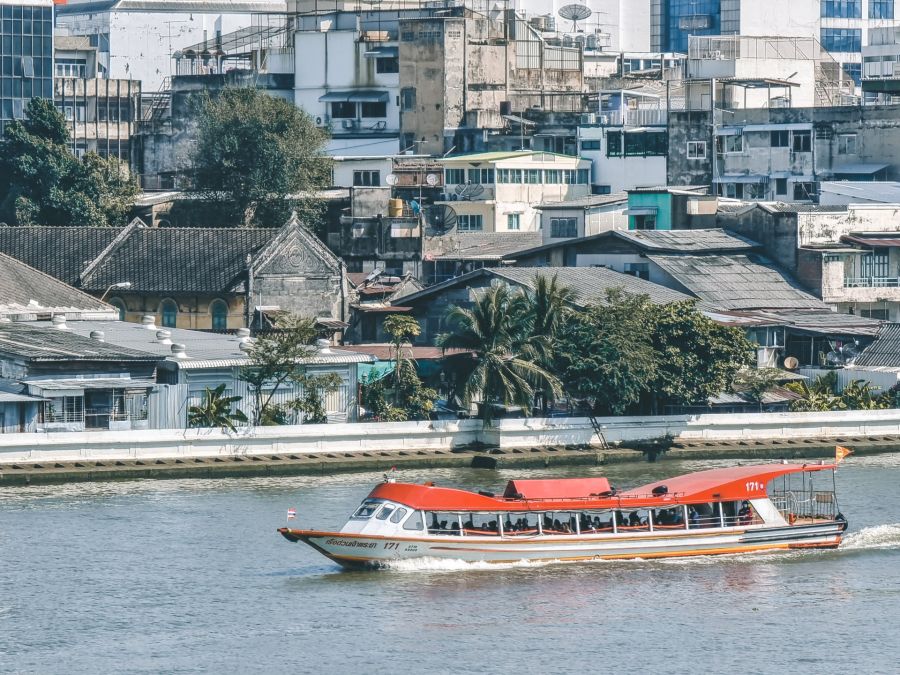 Bateau-taxi sur un canal devant immeubles urbains à Bangkok