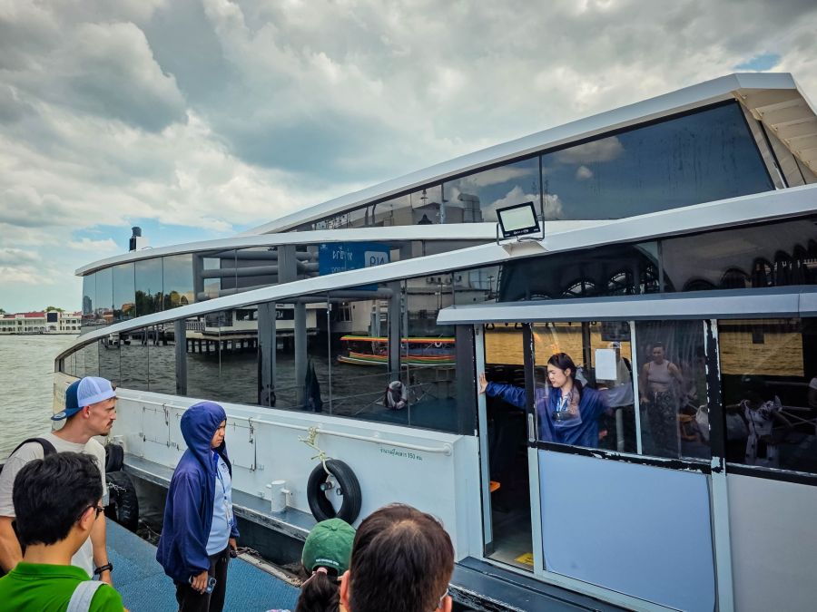 Passagers embarquant sur un bateau fluvial sous ciel nuageux