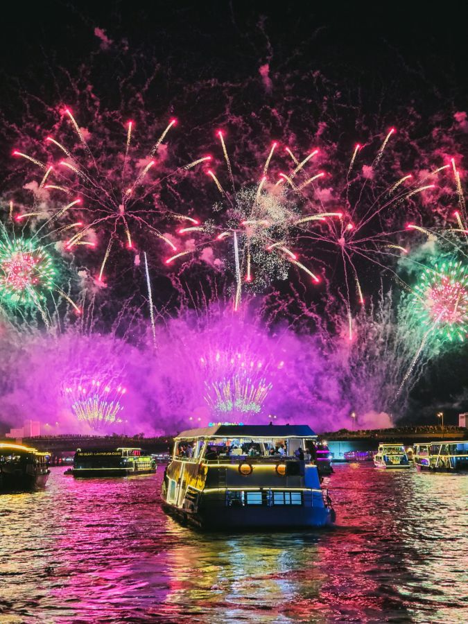 Feux d’artifice colorés au-dessus de bateaux sur un fleuve