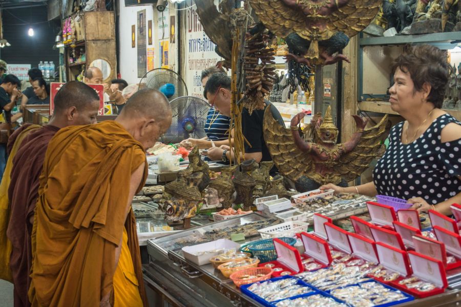 Moines bouddhistes devant un étal d’amulettes en Thaïlande