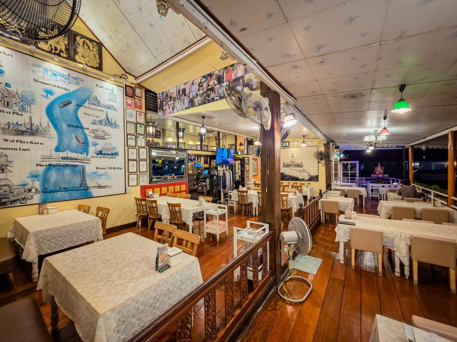 Salle de restaurant thaïlandais avec tables, ventilateurs et décorations murales