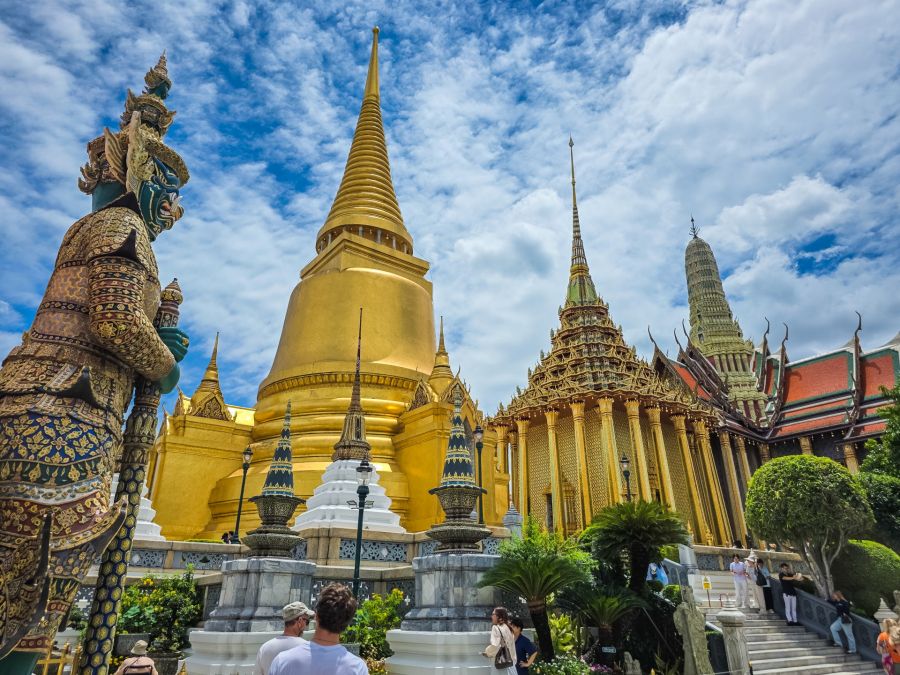 Temple thaïlandais doré avec statue gardienne et stupa
