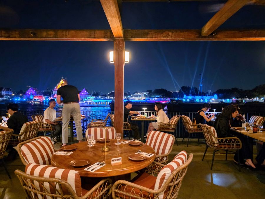 Terrasse de restaurant nocturne avec vue sur rivière illuminée