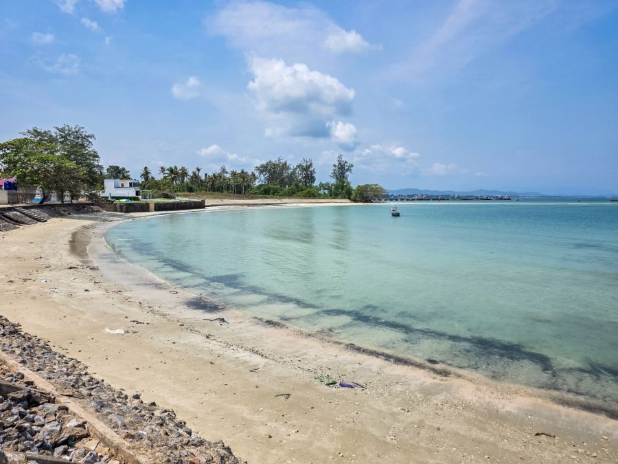 Tropical beach, turquoise water and a boat under a cloudy sky