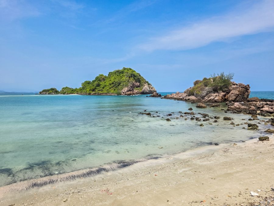 Tropical beach, turquoise water, rocks and a green islet