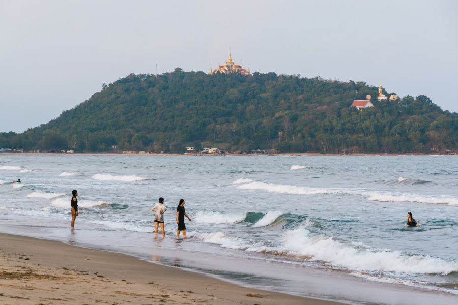 Bathers on the beach facing a golden temple