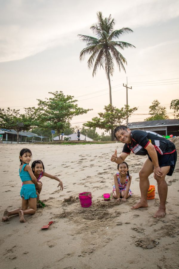 Father and three daughters building sandcastles