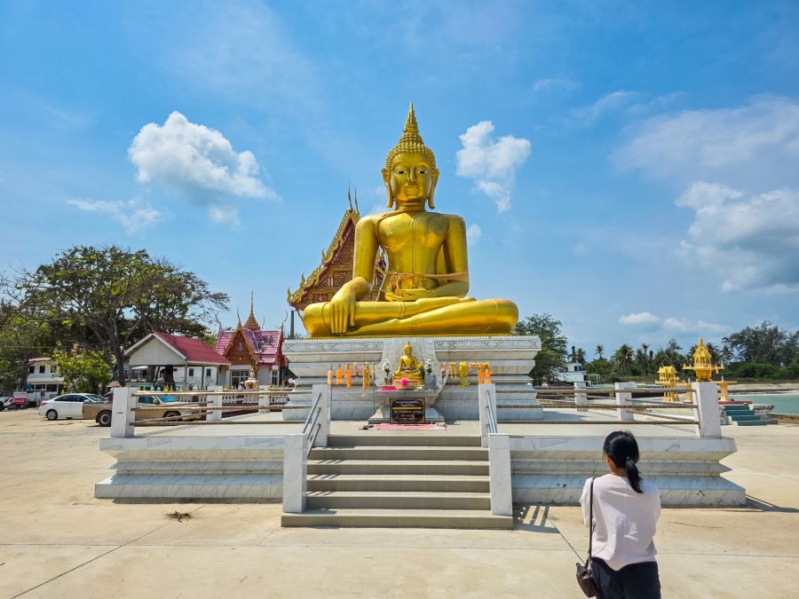 Large golden Buddha statue in front of a Thai temple