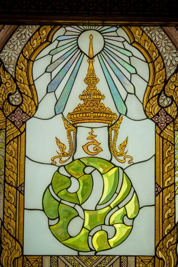 Ornate stained glass window depicting a radiant gold and green symbol