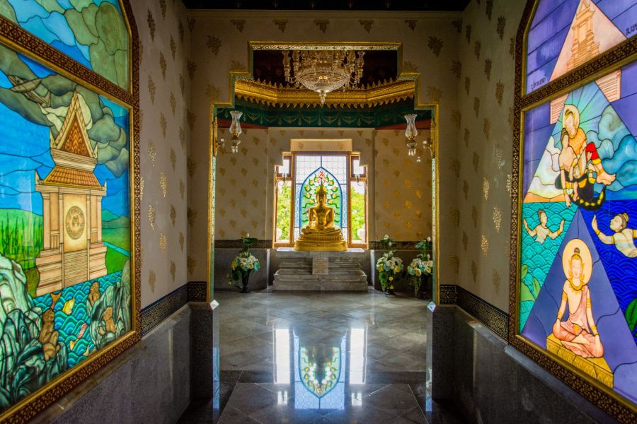 Golden Buddha statue in a temple with stained-glass windows