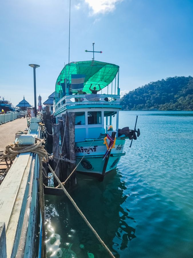 Bateau turquoise amarré au quai sous un ciel bleu