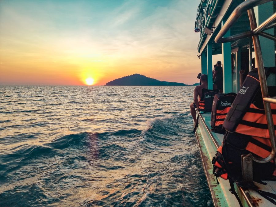 Bateau avec passagers au coucher du soleil près d’une île