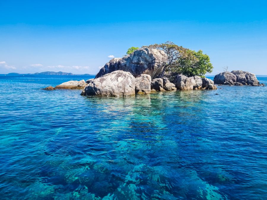 Îlot rocheux arboré dans une mer turquoise