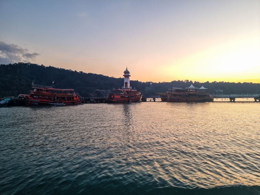 Bateaux près d’un phare au coucher du soleil