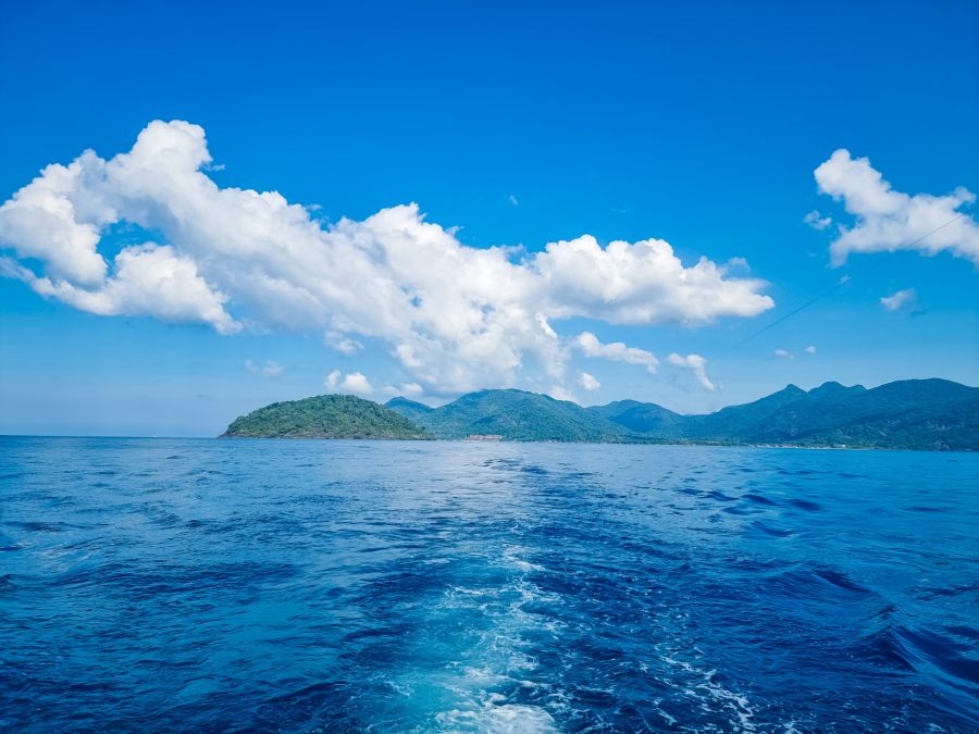 Mer turquoise, îles montagneuses et nuages blancs sous ciel bleu