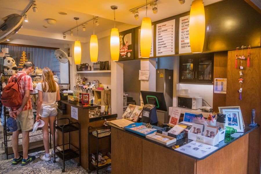 Clients au comptoir d’un café chaleureux éclairé de suspensions