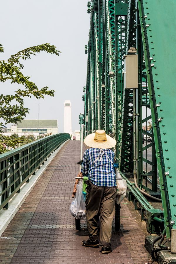 Personne poussant un chariot sur un pont métallique vert
