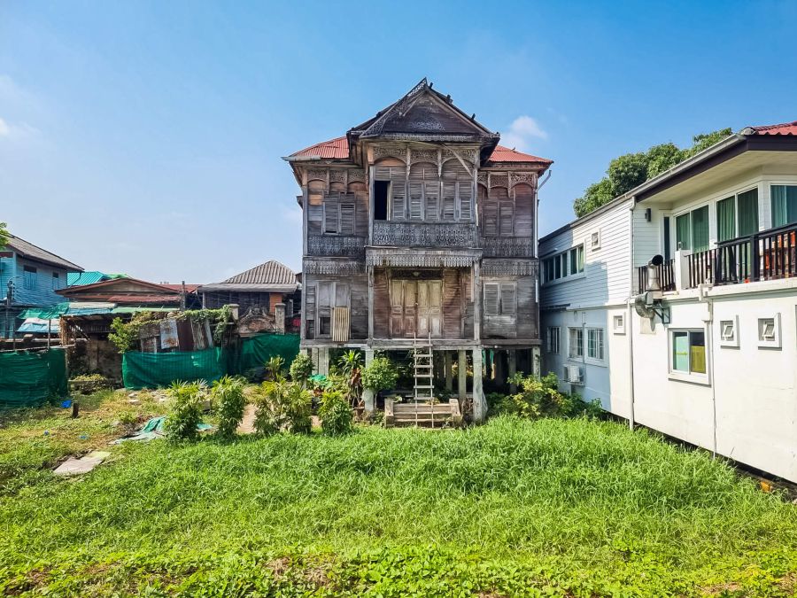 Maison traditionnelle en bois sur pilotis, entourée d’habitations