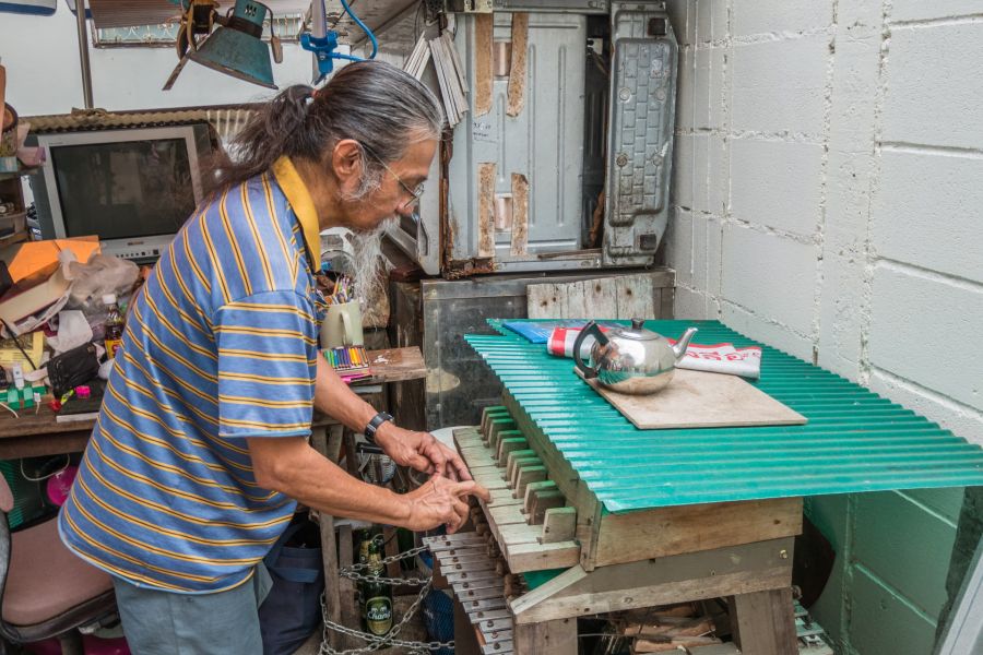 Artisan réglant un ancien orgue mécanique dans son atelier