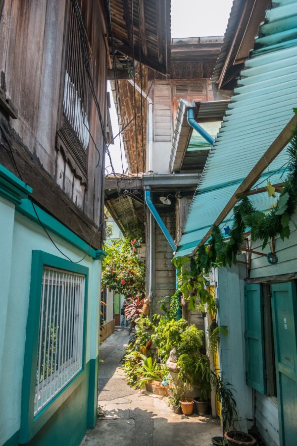 Ruelle étroite entre maisons en bois et plantes tropicales