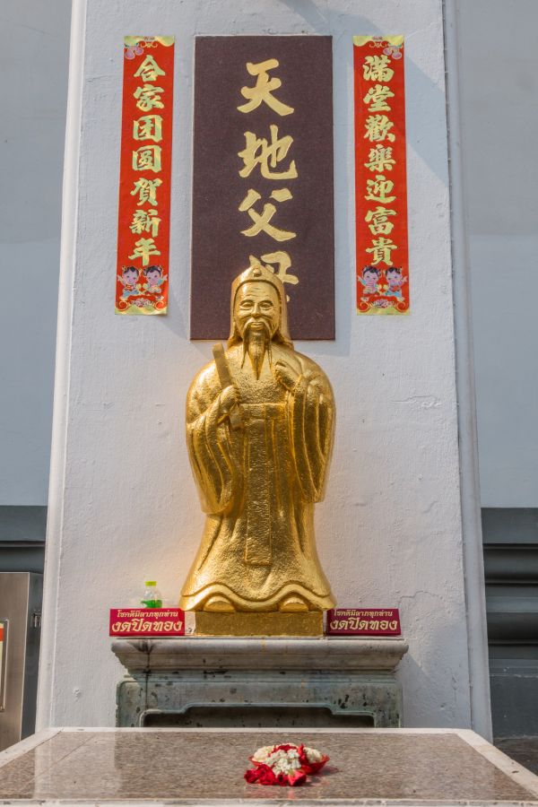 Statue dorée chinoise devant inscriptions et offrandes florales