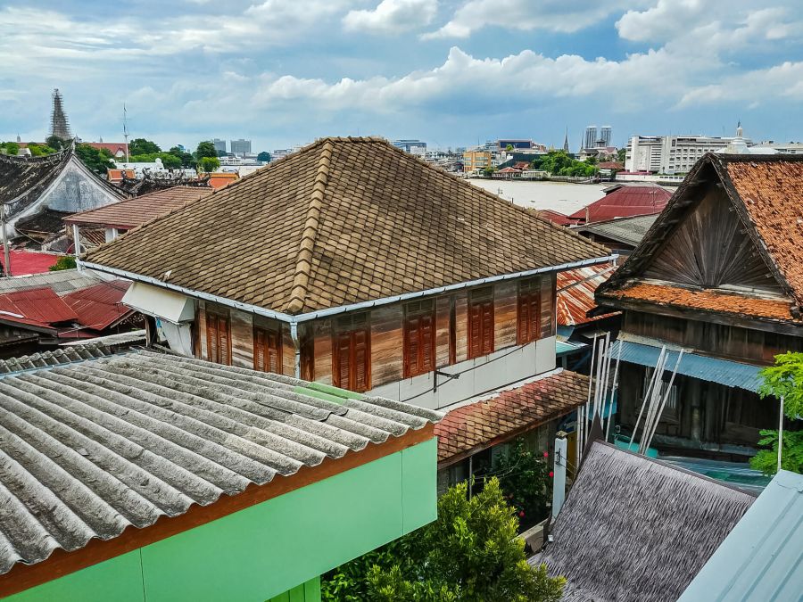 vue depuis les toits gauche baan kudee jin museum bangkok Maisons traditionnelles aux toits variés face à la ville