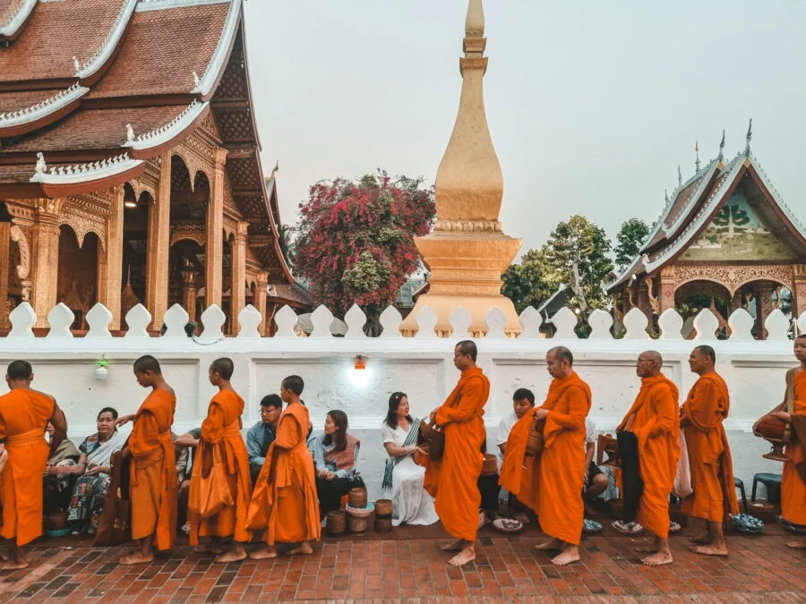 alignment of monks in front of temple ceremony tak bat luang prabang