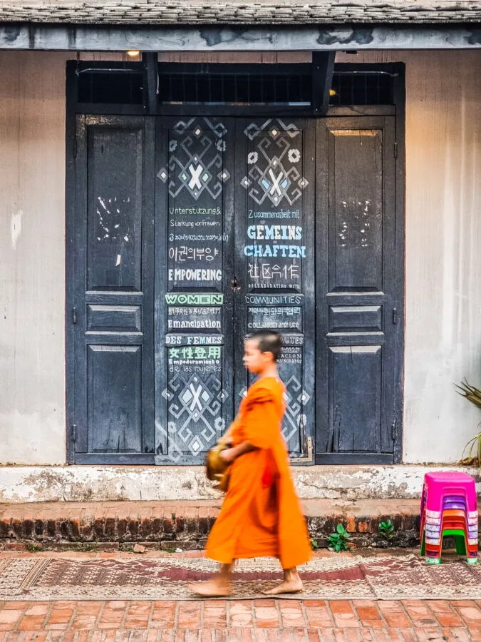 monk walking past house morning luang prabang