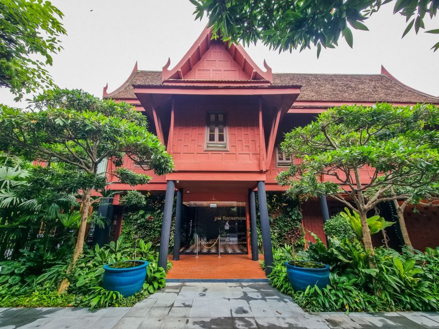 Façade traditionnelle thaïlandaise rouge entourée d’un jardin luxuriant