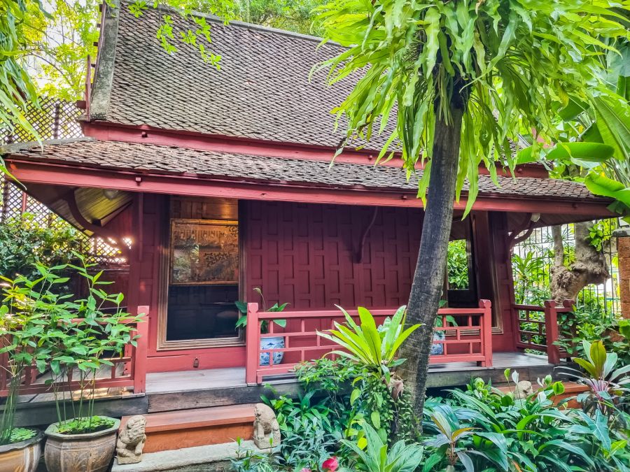 Maison traditionnelle rouge entourée d’une végétation tropicale luxuriante