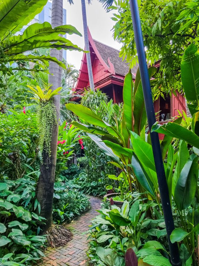 Maison traditionnelle rouge nichée dans un jardin tropical luxuriant