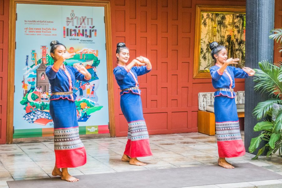 Trois danseuses thaïlandaises exécutent une danse traditionnelle en costume bleu.