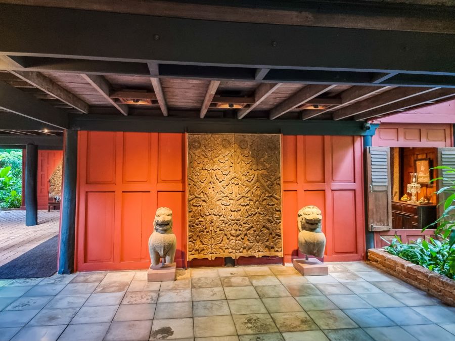 Porte sculptée encadrée de statues de lions dans un bâtiment traditionnel