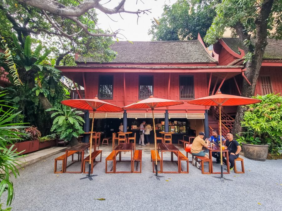 Café traditionnel rouge avec parasols au cœur d’un jardin tropical