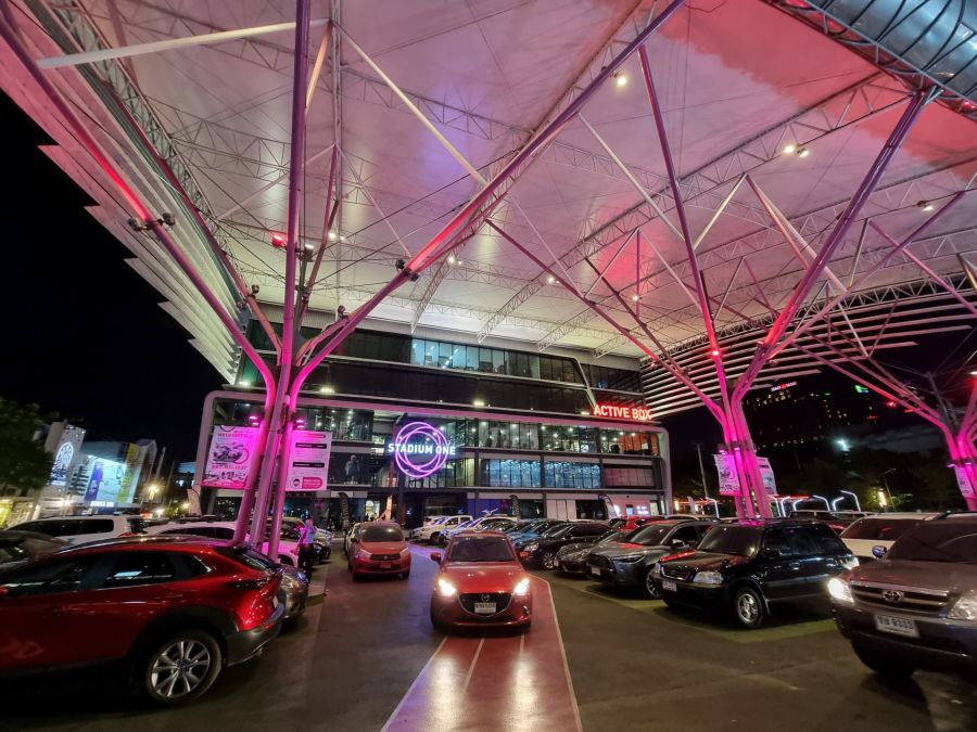 Parking nocturne devant Stadium One sous une vaste verrière éclairée