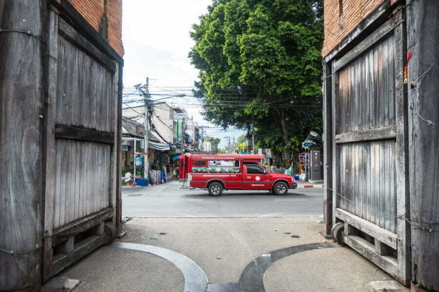 red songthaew passing in front of tha phae gate chiang mai