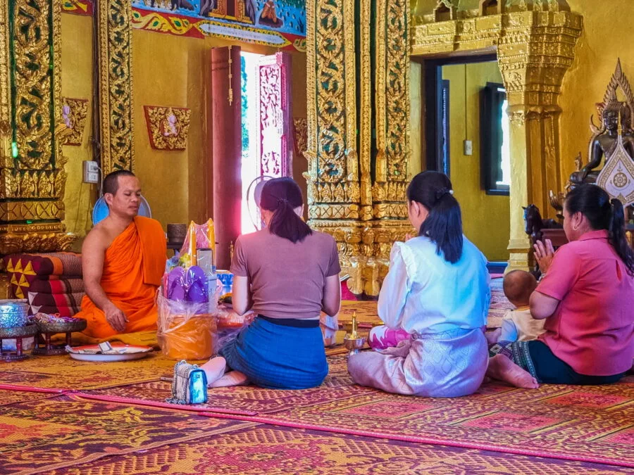 monk receiving offerings vat simuong vientiane